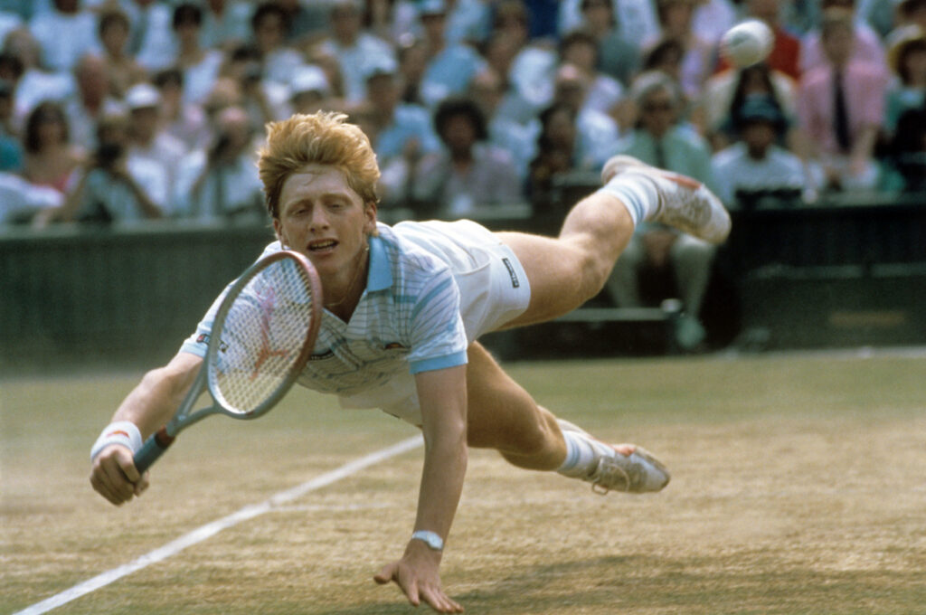 Der deutsche Tennisspieler Boris Becker hechtet während des Turniers in Wimbledon im Juli 1985 hinter einem Ball her. Als jüngster Spieler und erster Deutscher überhaupt gewann der ungesetzte Boris Becker am 7. Juli 1985 spektakulär gegen Kevin Curren in vier Sätzen das Wimbledon-Finale. (KEYSTONE/DPA/RUEDIGER SCHRADER)