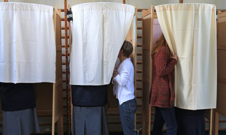 Two women assist voters at a polling station in Antwerp, Belgium, Sunday, May 25, 2014. Voters in 21 of the European Union's 28 member states go to vote Sunday on the final day of elections for the bloc's next parliament, with initial results from four days of polling due late in the evening. In Belgium people vote as well for the national and regional parliament. (AP Photo/Yves Logghe)