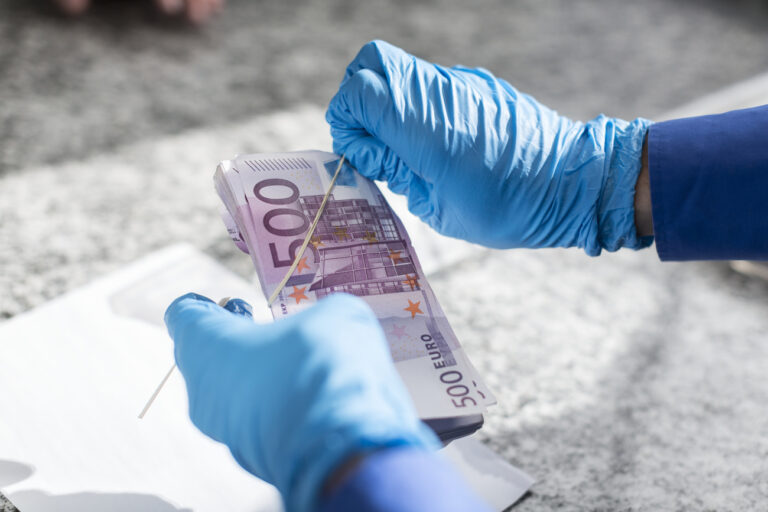 A member of the Swiss Border Guard Corps examines five hundred Euro bills for drug traces, captured at the border post in Chiasso, Switzerland, on October 23, 2014. (KEYSTONE/Gaetan Bally)