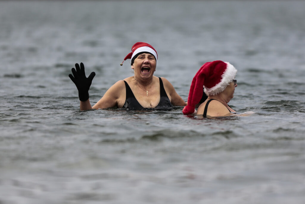Members of the winter and ice swimming club 'Seehunde Berlin', (Berlin Seals), wearing Christmas themed hats attend the annual Christmas Swimming at the chilly Oranke Lake in Berlin, Thursday, Dec. 25, 2014. Every Christmas the club arrange a swim at the lake. (AP Photo/Markus Schreiber)
