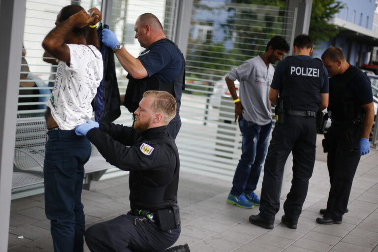 German federal police officers check refugees who arrived without documents at the main station in Rosenheim, Germany, Tuesday, July 28, 2015. (AP Photo/Matthias Schrader)