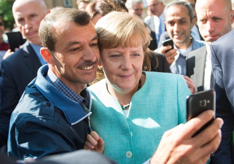 epa04923489 German Chancellor Angela Merkel (R) has a selfie taken with a refugee during a visit to a refugee reception centre in Berlin, Germany, 10 September 2015. Germany can deal with the arrival of hundreds of thousands of refugees without cutting social welfare benefits or raise taxes, Vice Chancellor Sigmar Gabriel said on 10 September, during a debate in parliament on next year's budget. Germany expects 800,000 asylum seekers this year, four times more than last year and more than any other country in the European Union, which is split on how to deal with the biggest refugee crisis since World War II. EPA/BERND VON JUTRCZENKA