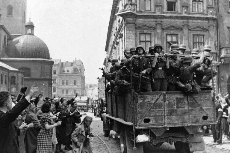 Inhabitants of the former Soviet-occupied Polish city of Lwow wave at a passing truckload of German soldiers as Nazi troops take over the city on July 2, 1941, according to theÂ caption passed through German government censors. The city is now known as Lviv in Ukraine.Â (AP Photo)
