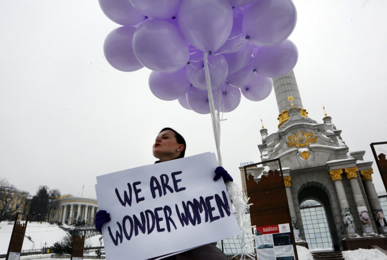 A woman holds balloons and a poster to mark International Women's Day in central Kiev, Ukraine, Thursday, March 8, 2018. (AP Photo/Efrem Lukatsky)
