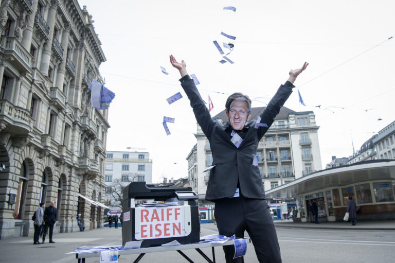 Ein Vollgeld-Aktivist mit einer Pierin Vincenz-Maske wirft gedruckte Tausender Noten in die Luft, anlaesslich einer Aktion zur Causa 