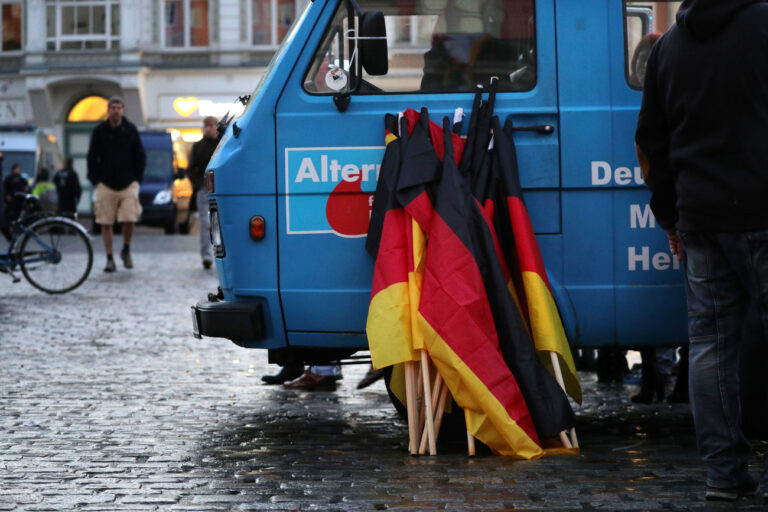 22.09.2018, Mecklenburg-Vorpommern, Rostock: Deutschlandfahnen lehnen am Rande einer Kundgebung der AfD an einem AfD-Fahrzeug. Die Kundgebung stand unter dem Motto 