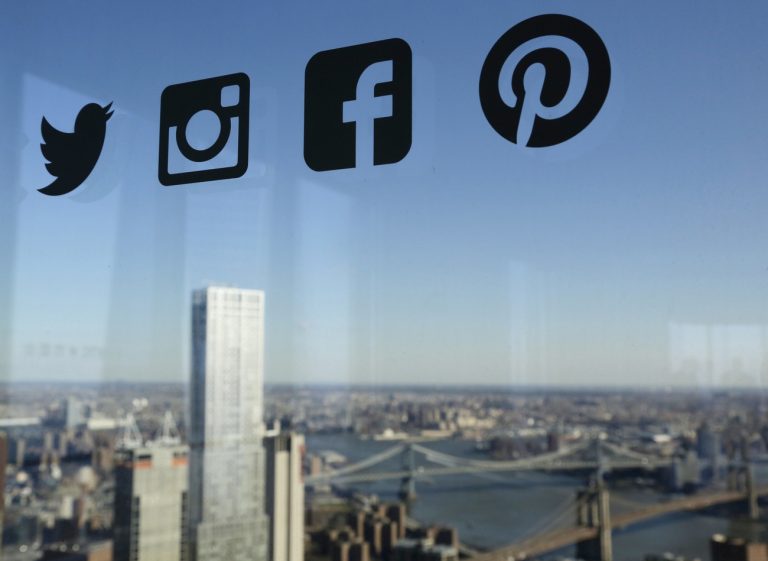 FILE- In this Jan. 13, 2016, file photo, Icons for Twitter, Instagram, Facebook and Pinterest are displayed on a window in New York. Nearly half of U.S. households carry credit card debt, which means many of the friends making you jealous on Instagram may not be able to afford the vacations they post about. (AP Photo/Mark Lennihan, File)