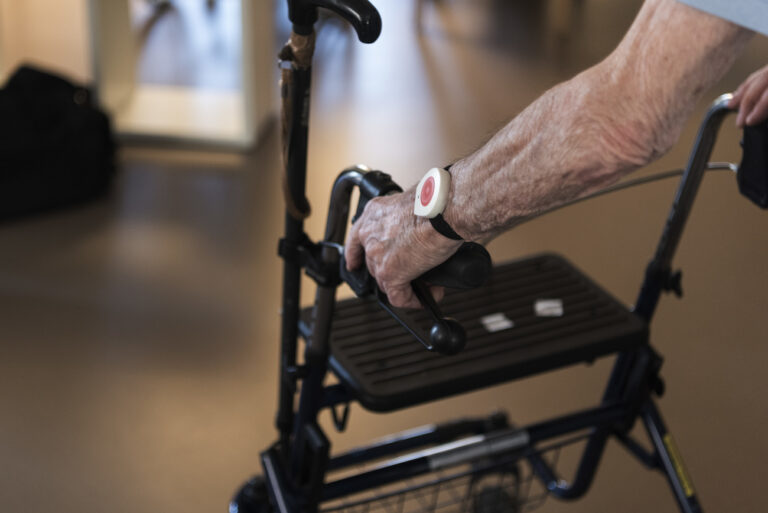 A resident wearing an emergency wrist transmitter walks in a hallway with a rollator, pictured at the retirement home Langgruet in Zurich, Switzerland, on March 22, 2019. (KEYSTONE/Christian Beutler)