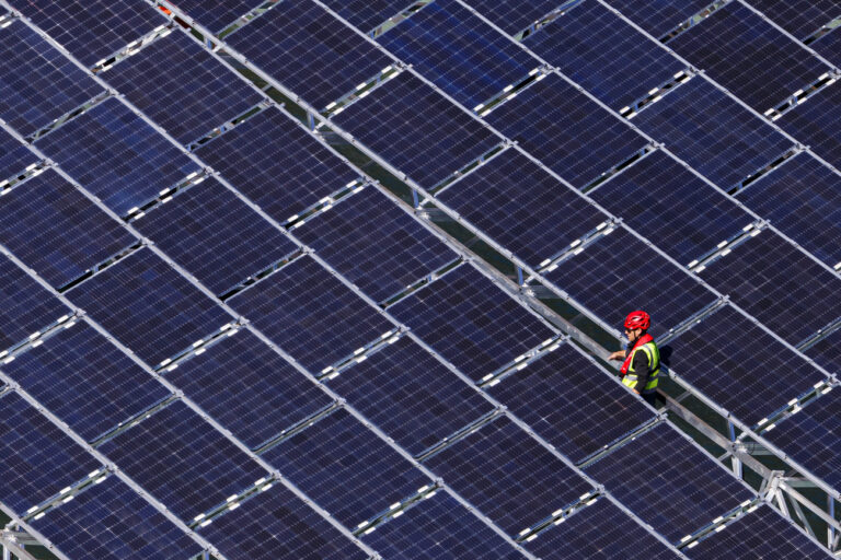 A worker assembles floating barges with solar panels on the 