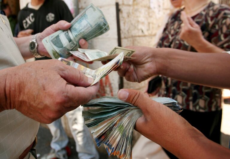 epa01054303 A street currency trader exchanges money outside the Arab Bank at the center of the West Bank town of Ramallah, 03 July 2007. Israel transferred millions of dollars to the Palestinian emergence government, to pay its employees, while skipping those who work for Hamas. EPA/ATEF SAFADI