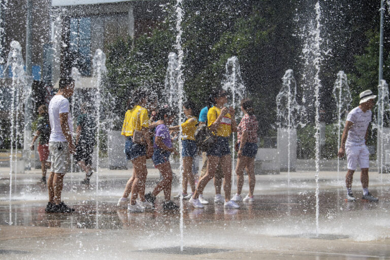 Des touristes profitent des jets d'eau pour se rafraichir et s'amuser, a la fontaine de la Place des Nations, par une chaude journee caniculaire d'ete a Geneve, ce mercredi 12 aout 2020. (KEYSTONE/Martial Trezzini)