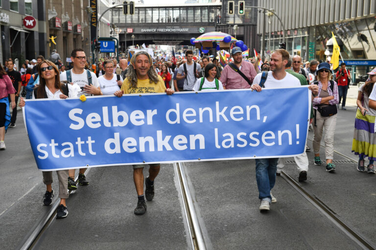 29.08.2020, Berlin: Teilnehmer gehen durch die Freidrichstraße bei einer Demonstration gegen die Corona-Maßnahmen mit einem Banner 