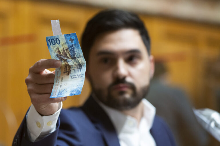 Cedric Wermuth, Nationalrat SP-AG, nimmt eine 100 Franken Banknote weg, die er waehrend seiner Rede an die Plexiglasscheibe geklebt hat, waehrend der Debatte um die Volksinitiative 