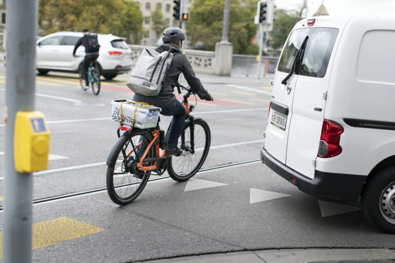 Ein E-Bike-Fahrer mit Helm faehrt am Limmatquai neben einem rechts abbiegenden Auto vorbei, fotografiert am 5. Oktober 2020 in Zuerich. (KEYSTONE/Gaetan Bally)