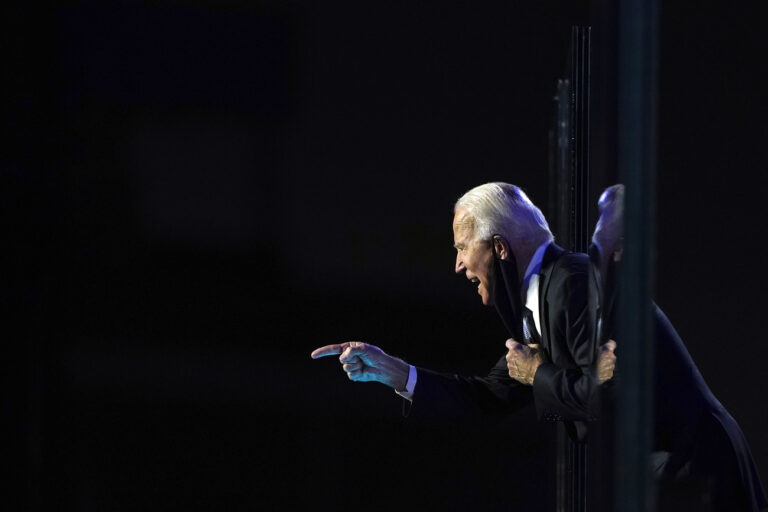 President-elect Joe Biden leans toward the cheering crowd, past the edge of protective glass on stage, Saturday, Nov. 7, 2020, in Wilmington, Del. (AP Photo/Carolyn Kaster)