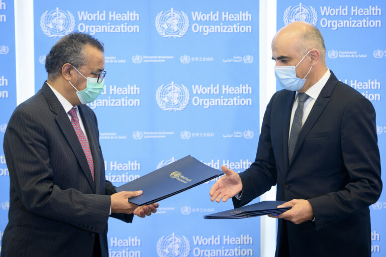 Swiss Interior and Health Minister Alain Berset, right, exchanges documents with Tedros Adhanom Ghebreyesus, left, Director General of the World Health Organization (WHO) during a bilateral meeting to signs BioHub Initiative with a global Covid-19 Pathogen repository in Spiez laboratory on the sideline of the opening of the 74th World Health Assembly, WHA, at the WHO headquarters, in Geneva, Switzerland, Monday, May 24, 2021. (KEYSTONE POOL/Laurent Gillieron)