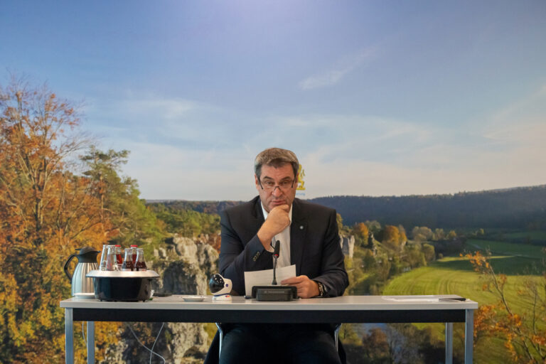 03.11.2021, Bayern, München: Markus Söder (CSU), Ministerpräsident von Bayern, sitzt vor Beginn einer Online-Sitzung des bayerischen Kabinetts nach der Sommerpause auf seinen Platz vor einer herbstlichen Fotowand. Das bayerische Kabinett will über die Verschärfung der Corona-Maßnahmen verhandeln. Foto: Peter Kneffel/dpa +++ dpa-Bildfunk +++ (KEYSTONE/DPA/Peter Kneffel)