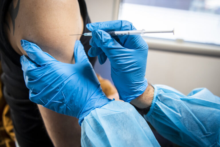 Une personne de l'equipe de vaccination administre avec une seringue une dose de vaccin contre le Covid dans une unite mobile de vaccination sur la place de la Riponne lors de la Semaine nationale de la vaccination le mardi 9 novembre 2021 a Lausanne. (KEYSTONE/Jean-Christophe Bott)