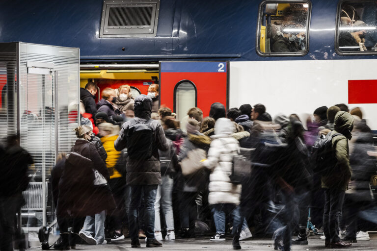 Commuters wear face masks to curb the spread of COVID-19 as they get on a public train in Zurich on Tuesday, November 30, 2021. (KEYSTONE/Michael Buholzer)