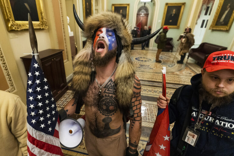 Jacob Anthony Chansley, center, with other insurrectionists who supported then-President Donald Trump, are confronted by U.S. Capitol Police in the hallway outside of the Senate chamber in the Capitol, Jan. 6, 2021, in Washington. Chansley, was among the first group of insurrectionists who entered the hallway outside the Senate chamber. (AP Photo/Manuel Balce Ceneta)