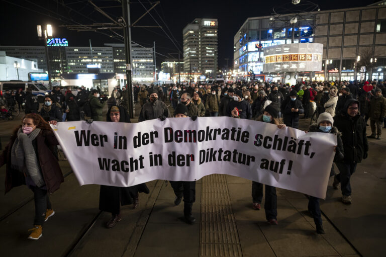 17.01.2022, Berlin: Menschen laufen auf einer Demonstration gegen die Corona-Maßnahmen mit einem Banner mit der Aufschrift 