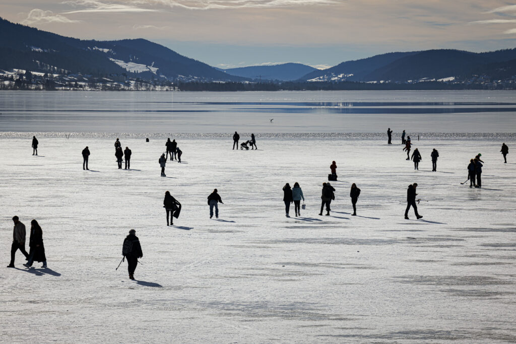 People walk on the partially frozen Lac de Joux lake in Le Pont in the Vallee de Joux, western Switzerland, Saturday, January 29, 2022. (KEYSTONE/Valentin Flauraud)