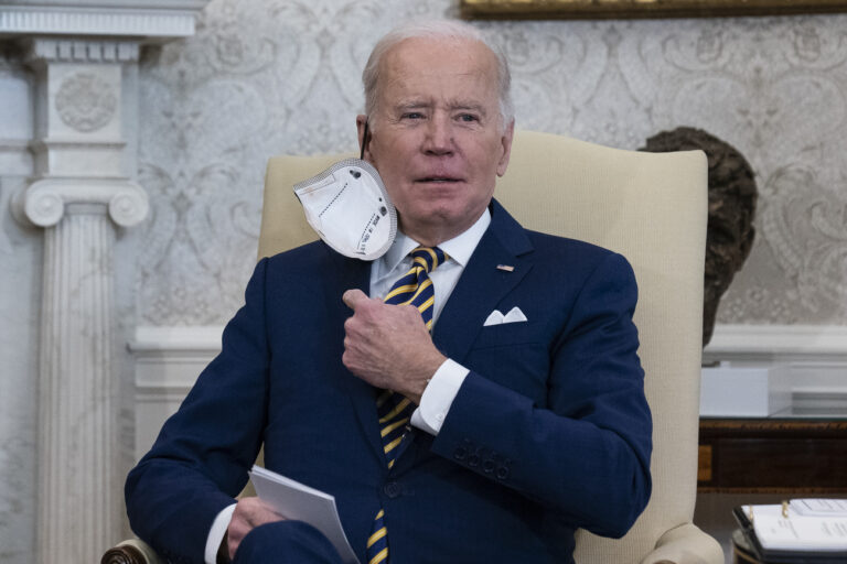 President Joe Biden removes his protective face mask before speaking during a meeting with the Qatar's Emir Sheikh Tamim bin Hamad Al Thani in the Oval Office of the White House, Monday, Jan. 31, 2022, in Washington. (AP Photo/Alex Brandon)