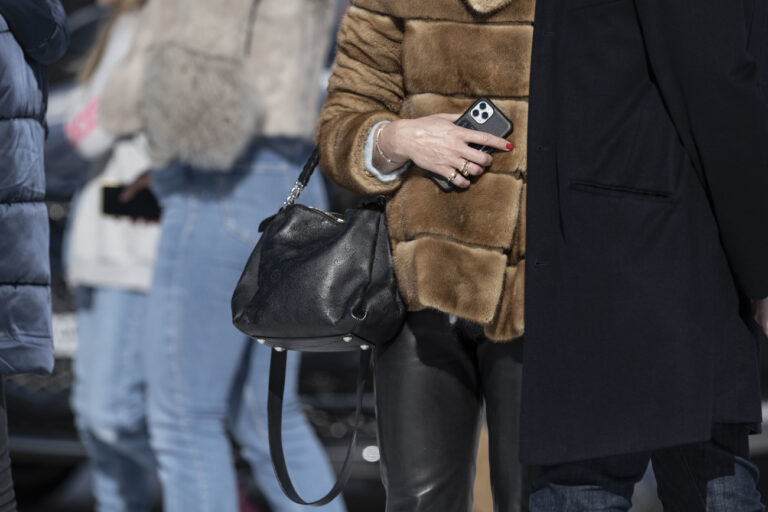 Eine Frau mit Pelzmantel, Handtasche und Smartphone, fotografiert im Rahmen des White Turf, am Sonntag, 20. Februar 2022 in St. Moritz. (KEYSTONE/Christian Beutler)
