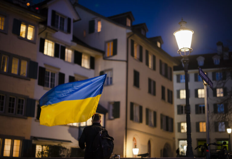 A protestors holding a Ukraininen flag walks in the old town of Zuerich after before a demonstration against the Russian invasion of Ukraine in Zuerich, Switzerland, on Monday, February 28, 2022. (KEYSTONE/Michael Buholzer)
