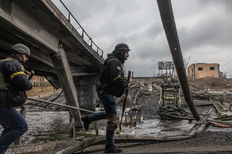 epa09799527 Ukrainian military members walk on a bridge destroyed by shelling in Irpin city, Kyiv (Kiev) province, Ukraine, 03 March 2022. Russian troops entered Ukraine on 24 February prompting the country's president to declare martial law and triggering a series of severe economic sanctions imposed by Western countries on Russia. (KEYSTONE/EPA/ROMAN PILIPEY)