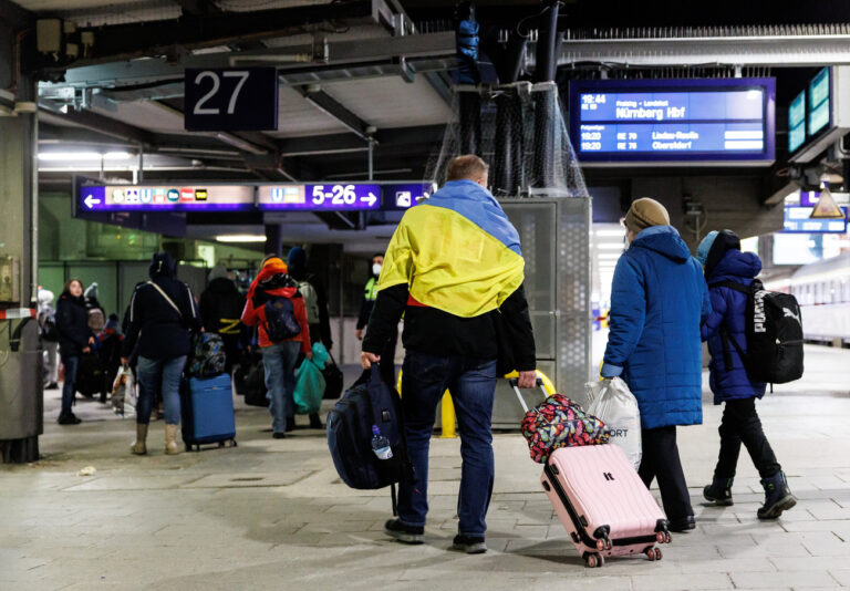 12.03.2022, Bayern, München: Ein Helfer der Caritas (l) begleitet ukrainische Flüchtlinge nach ihrer Ankunft mit einem Sonderzug mit circa 400 Flüchtlingen aus der Ukraine zur Registrierung am Münchner Hauptbahnhof. Der Zug mit ursprünglich circa 1500 Flüchtlingen kommt aus dem polnischen Dorf Dorohusk an der Grenze zur Ukraine - zahlreiche Flüchtlinge waren bereits an anderen Bahnhöfen ausgestiegen. Foto: Matthias Balk/dpa +++ dpa-Bildfunk +++ (KEYSTONE/DPA/Matthias Balk)