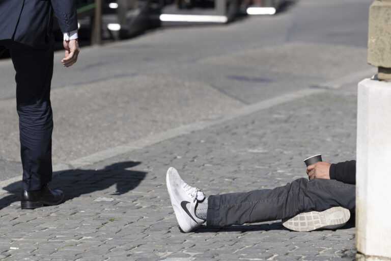 Un homme passe vers un mendiant qui fait la manche sur la place du Bourg-de-Fourg, ce vendredi 25 mars 2022 a Geneve. (KEYSTONE/Salvatore Di Nolfi)