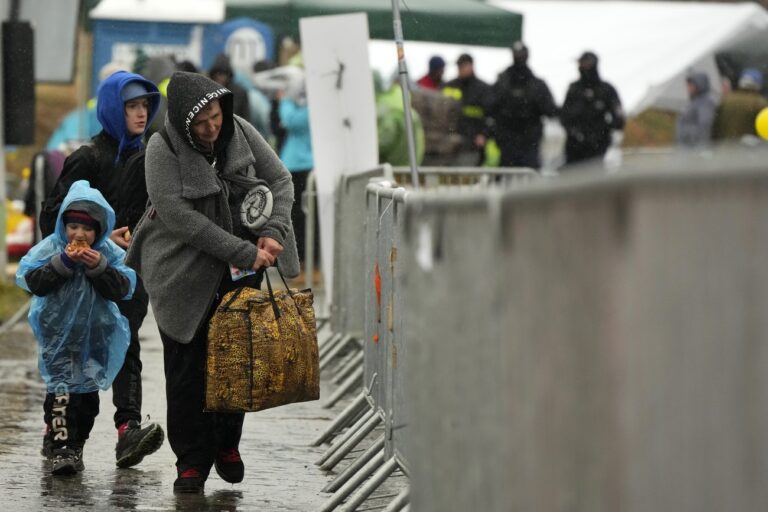 A Ukrainian woman carrying her belongings, arrives with two kids at the border crossing in Medyka, southeastern Poland, Thursday, March 31, 2022. The talks between Ukraine and Russia will resume on Friday as NATO Secretary-General says Russia does not appear to be scaling back its military operations in Ukraine but is instead redeploying forces to the eastern Donbas region. (AP Photo/Sergei Grits)