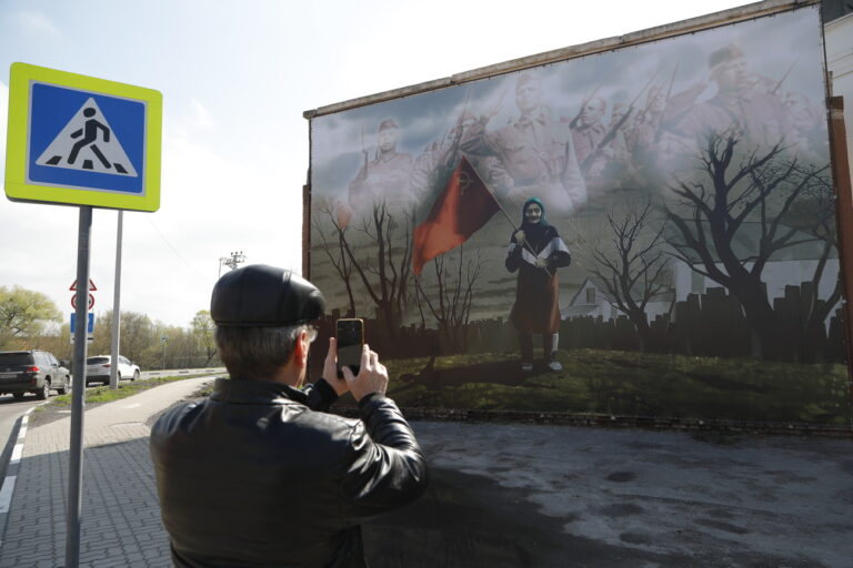 8171399 21.04.2022 A pedestrian takes pictures of a banner depicting an elderly woman from the Ukrainian village of Dmytrivka outside Kiev who mistook Ukrainian servicemen for Russian troops and came to greet them with a Soviet flag as Russia's military operation in Ukraine continues, on a residential building in the town of Shebekino, Belgorod region, Russia. Anton Vergun / Sputnik (KEYSTONE/SPUTNIK/Anton Vergun)