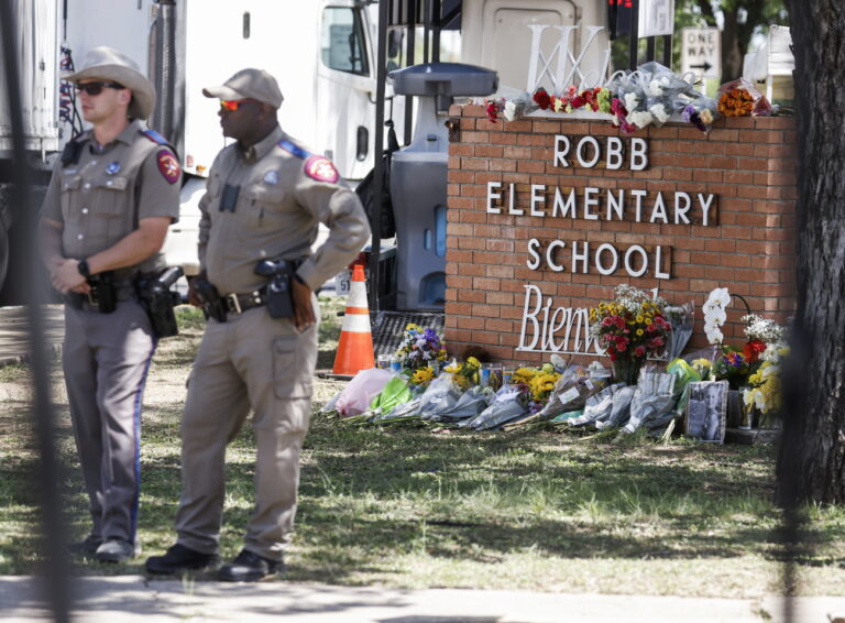 epa09976024 Texas Highway Patrol officers stand near a memorial of flowers at the scene of a mass shooting at the Robb Elementary School in Uvalde, Texas, USA, 25 May 2022. According to Texas officials, at least 19 children and two adults were killed in the shooting. The eighteen-year-old gunman was killed by responding officers. EPA/TANNEN MAURY