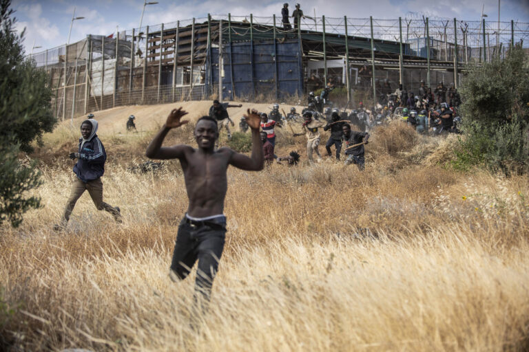 Migrants run on Spanish soil after crossing the fences separating the Spanish enclave of Melilla from Morocco in Melilla, Spain, Friday, June 24, 2022. Dozens of migrants stormed the border crossing between Morocco and the Spanish enclave city of Melilla on Friday in what is the first such incursion since Spain and Morocco mended diplomatic relations last month. (KEYSTONE/AP Photo/Javier Bernardo)