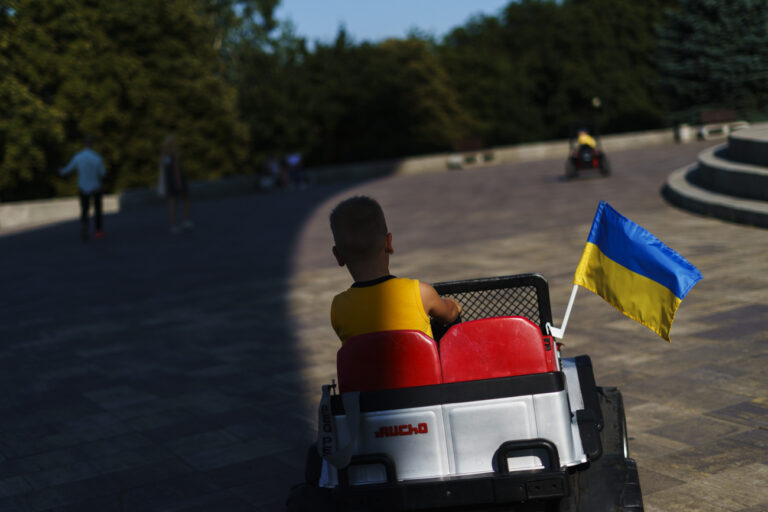 A boy drives a toy vehicle decorated with the flag of Ukraine, Sunday, July 31, 2022, in Kyiv, Ukraine. (AP Photo/David Goldman)