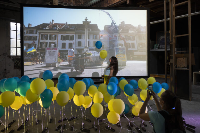 Ukrainerinnen fotografieren sich vor einem Filmleinwand, waehrend einer Veranstaltung zum Ukrainischen Tag der Flagge in der Veranstaltungsplattform Dispo, am Dienstag, 23. August 2022 in Biel. (KEYSTONE/Peter Klaunzer)