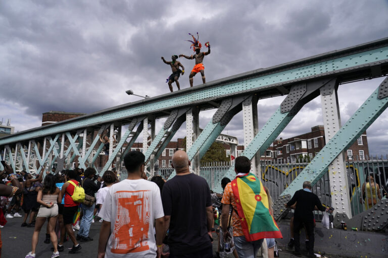 Revellers dance on top of a railway bridge during the annual Notting Hill Carnival in west London, Monday, Aug. 29, 2022. The carnival which returned to the streets for the first time in two years, after it was thwarted by the pandemic, is one of the largest festival celebrations of its kind in Europe. (AP Photo/Alberto Pezzali)