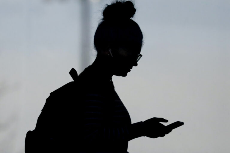 FILE - A woman checks her phone in Orem, Utah, on Nov. 14, 2019. A survey of people ages 16 to 40 finds that millennials and Generation Z follow the news, but they aren't that happy with what they're seeing. The study conducted by The Associated Press-NORC Center for Public Affairs Research and the American Press Institute says 79% of people follow news daily, contrary to perceptions that many are tuned out. (AP Photo/Rick Bowmer, File)