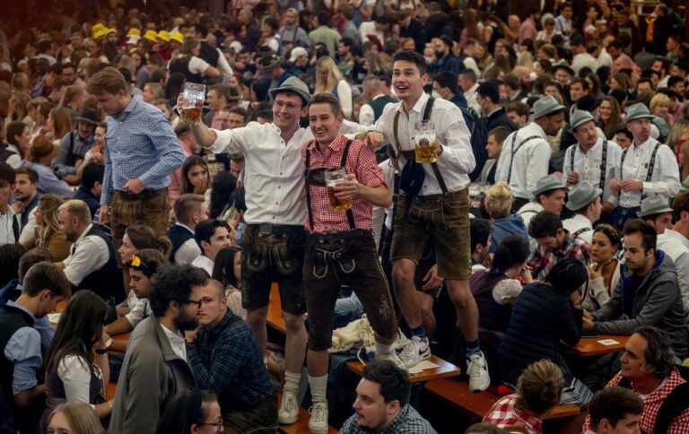 Visitors stand on a table in one of the beer tents on the opening day of the 187th Oktoberfest beer festival in Munich, Germany, Saturday, Sept. 17, 2022. (KEYSTONE/AP Photo/Michael Probst)