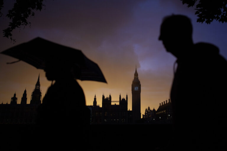 People walk past the sunset on Big Ben as they queue to pay their respects to late Queen Elizabeth II who's lying in state at Westminster Hall in London, England, Sunday, Sept. 18, 2022. The funeral of Queen Elizabeth II, Britain's longest-reigning monarch, takes place on Monday. (AP Photo/Christophe Ena)