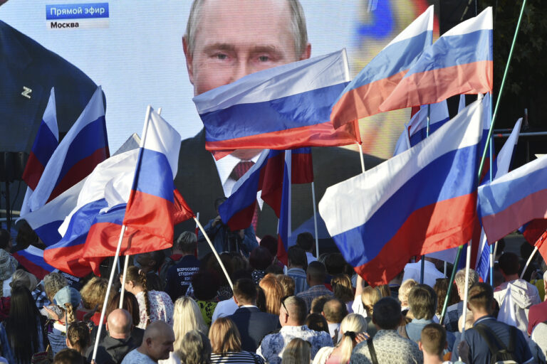 People watch on a large screen, as Russian President Vladimir Putin delivers his speech after a ceremony to sign the treaties for four regions of Ukraine to join Russia in the Moscow's Kremlin, during a meeting in Sevastopol, Crimea, Friday, Sept. 30, 2022. The signing of the treaties making the four regions part of Russia follows the completion of the Kremlin-orchestrated 