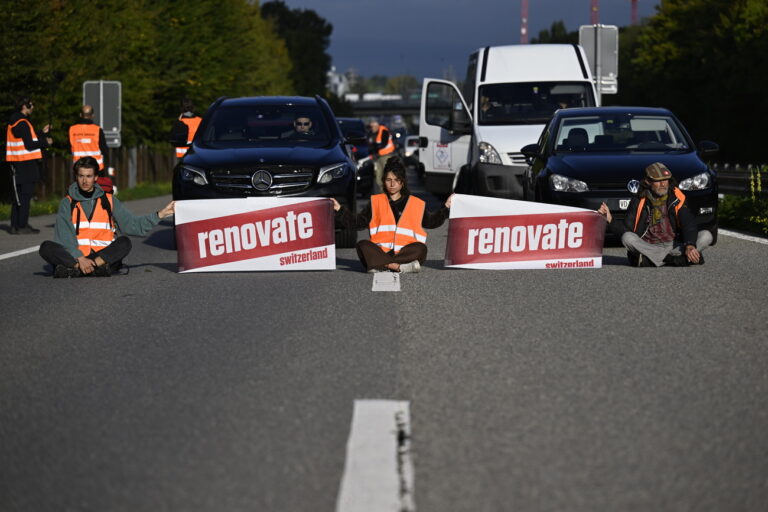 Environmental activists members of Renovate Switzerland sit down in the road during a roadblock action of the A1 motorway, in Lausanne, Switzerland, Tuesday, October 4, 2022.(KEYSTONE/Laurent Gillieron)