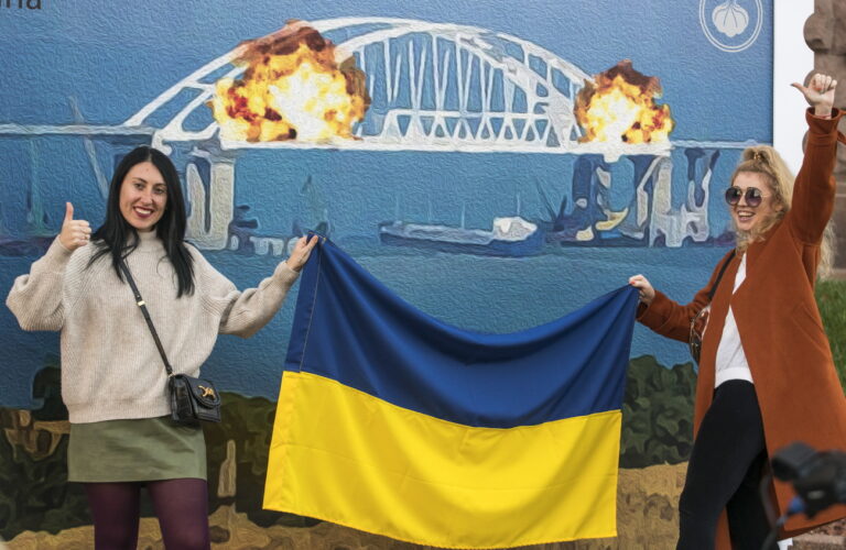 epa10231170 Ukrainians take selfies and pose for photos in front of an artist collective's' impression of explosions at Kerch Strait bridge on a stamp called 