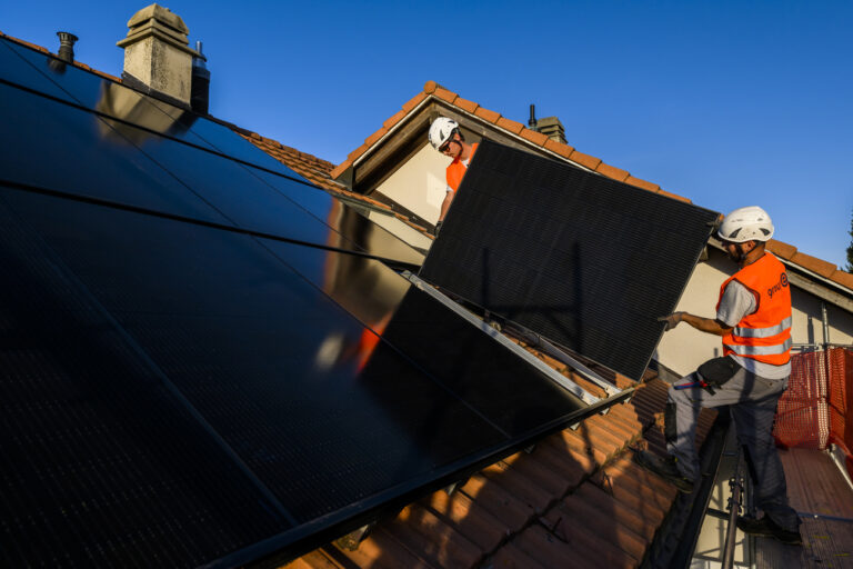 Deux installateurs du Groupe E installent un panneau solaire photovoltaique sur le toit d'une habitation le mercredi 2 novembre 2022 a Fribourg. (KEYSTONE/Jean-Christophe Bott)
