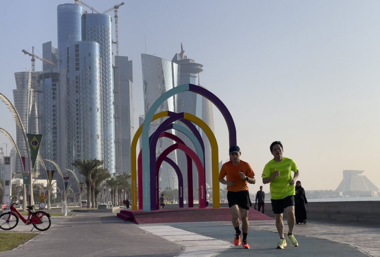 epa10290850 People jog near the colourful arches with the FIFA World Cup banner at the Doha Corniche, in Doha, Qatar, 06 November 2022. The FIFA World Cup Qatar 2022 will take place from 20 November to 18 December 2022 in Qatar. EPA/NOUSHAD THEKKAYIL