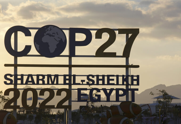 The sun sets behind signage for the COP27 U.N. Climate Summit in Sharm el-Sheikh, Egypt, Wednesday, Nov. 9, 2022. (AP Photo/Thomas Hartwell)