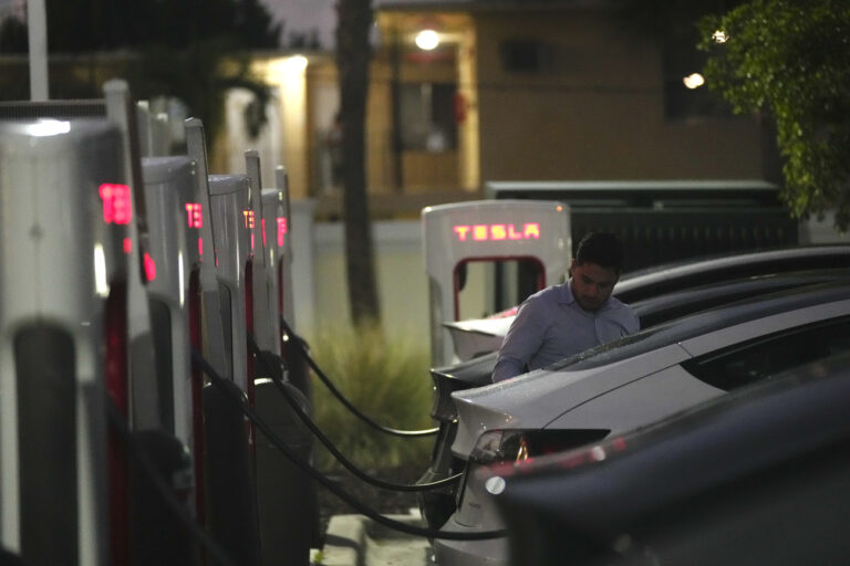 A driver charges his car at a Tesla Supercharger station, Wednesday, Nov. 16, 2022, in Miami. (AP Photo/Rebecca Blackwell)