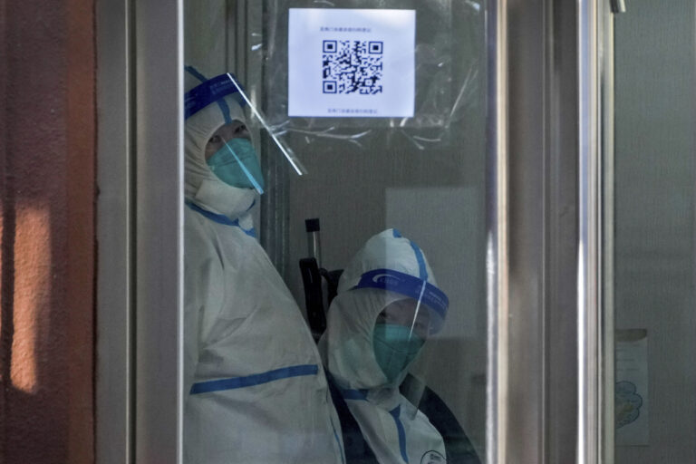 Medical workers in protective gear look out from the fever clinic at a hospital in Beijing, Monday, Dec. 19, 2022. Chinese health authorities on Monday announced two additional COVID-19 deaths, both in the capital Beijing, that were the first reported in weeks and come during an expected surge of illnesses after the nation eased its strict 